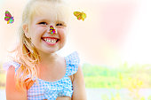 Portrait of laughing toddler pretty girl with butterfly. Fun time on the beach.  Happy childhood and freedom concept