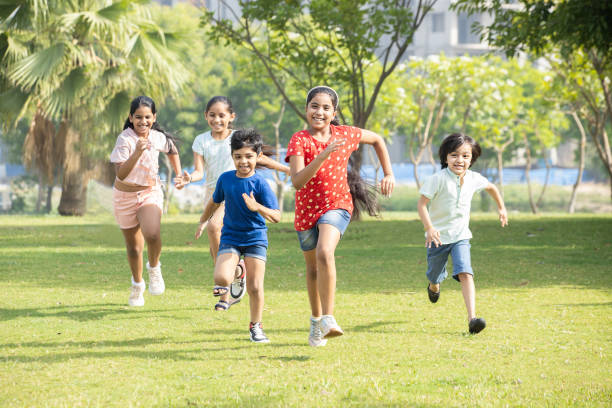 gruppo di bambini indiani allegri e giocosi che corrono all'aperto nel parco primaverile. bambini asiatici giocando in giardino. - attrezzatura per giochi allaperto foto e immagini stock