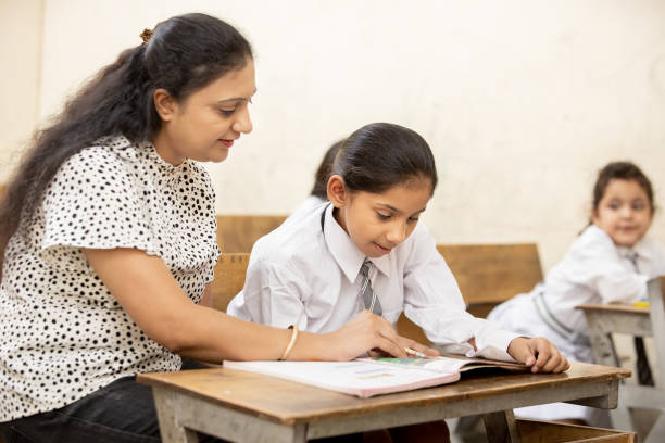 istock Indian mature teacher helping a student in elementary school lessons in classroom. female child studying in classroom, Girl Education concept. 1447832606