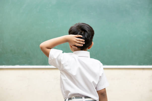 혼란스러운 인도 아이는 교실에서 빈 분필 보드를 보면서 머리를 긁적이며 학생의 학습 및 교육 개념에 문제가 있습니다. - asking teaching confusion solution 뉴스 사진 이미지