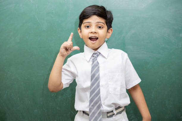 Smart little Indian schoolboy having an idea expression with wide open mouth finally found a solution, blank chalkboard. Education concept.