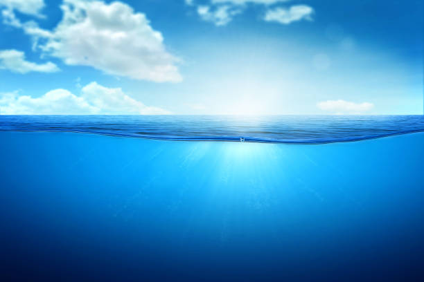 istock BLUE UNDER WATER waves and bubbles. Beautiful white clouds on blue sky over calm sea with sunlight reflection, Tranquil sea harmony of calm water surface. 1447837893