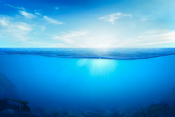 istock BLUE UNDER WATER waves and bubbles. Beautiful white clouds on blue sky over calm sea with sunlight reflection, Tranquil sea harmony of calm water surface. 1447837894