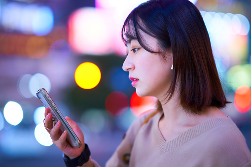 Young woman looking at smartphone in downtown at night