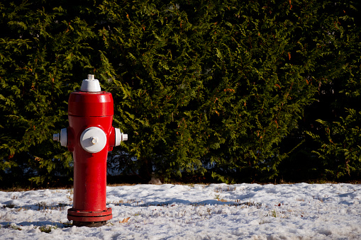 An image of a bright red fire hydrant in a snow covered residential area.