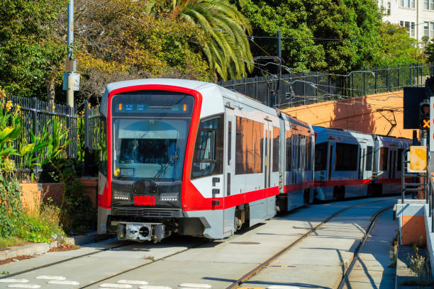 istock Tram or train with red and grey paint on railing with shrubs and trees in background in an urban part of the city downtown 1447846403