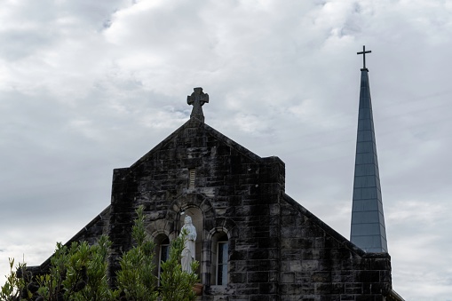 A steeple of a church in Vaucluse against a dark cloudy sky
