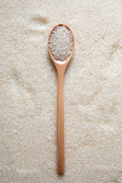 istock Top view of a stack of raw rice with a wooden spoon on it 1447849903