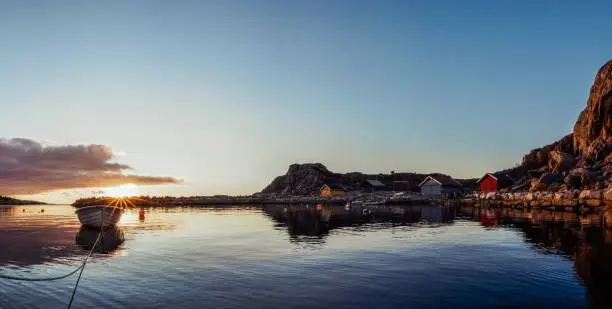 A seascape view with a wooden boat moored in the calm seawater and a small town in the background