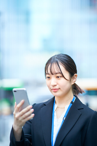 Young woman in suit looking at the screen of smartphone