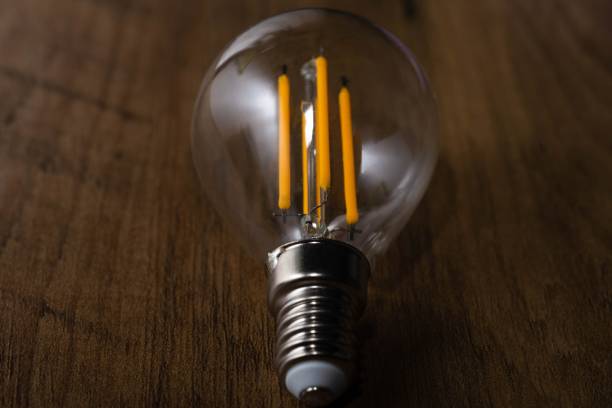 istock Closeup of a clear light bulb on a wooden surface 1447853637
