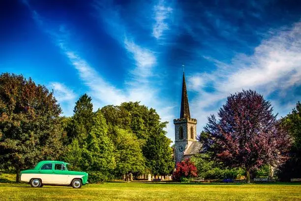 The view of a Ford Consul Mk1 parked in the greenery before the old English church