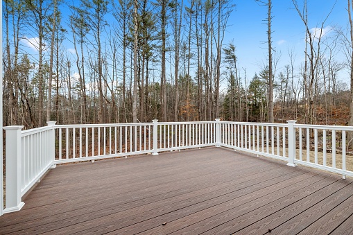 The decking boards of a porch with white railings in a suburb house