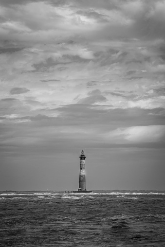 The vertical waterside grayscale shot of the Morris Island Lighthouse