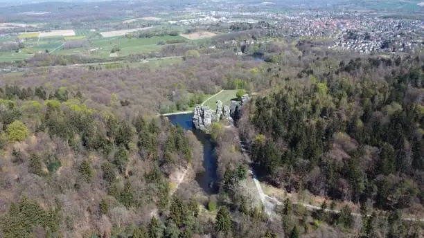 An aerial shot of the Externsteine sandstone rock formation surrounded by mostly dry forest