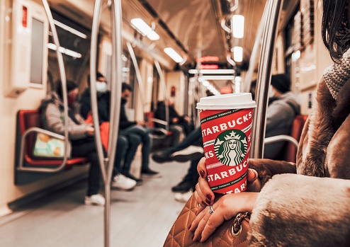 Budapest, Hungary – November 30, 2021: A closeup shot of a woman sitting in the metro train, holding a cup of Starbucks coffee