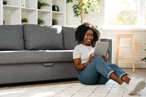 istock Young african woman using digital tablet and smiling while resting at home. 1447866013