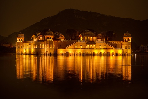 A scenic view of the Jal Mahal palace in the middle of the Man Sagar Lake illuminated at night