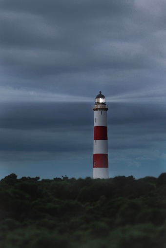 A vertical shot of red and white lighthouse on coast under gloomy cloudy sky, North Scotland