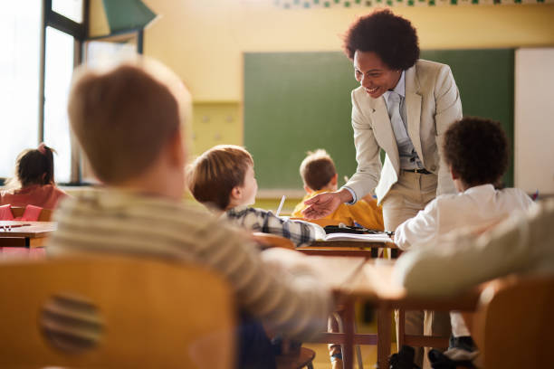 istock Happy black professor assisting schoolboy on a class at school. 1447868494