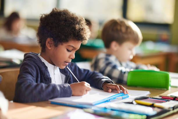 istock Black schoolboy and his friends on a class at elementary school. 1447868901