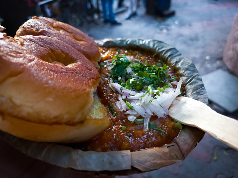 Indian Mumbai Street food Pav Bhaji, garnished with peas, onions, coriander, and Butter. Spicy thick curry made of out mixed vegetables served with pav. Blur background.