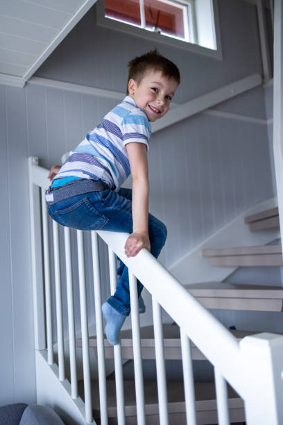 istock Boy sliding on the staircase in the house 1447880703