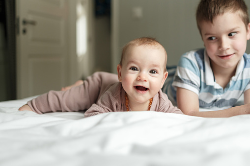 Two toddlers, a girl hugs a boy while playing at home on the floor, early child development concept