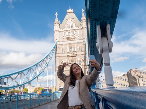 She poses on the Tower bridge, fun exploring the city, solo travel concept