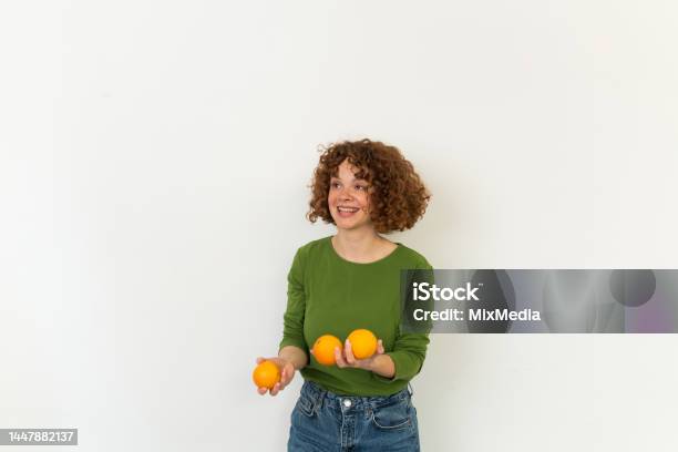 Studio Portrait Of A Cheerful Girl Juggling With Oranges Stock Photo - Download Image Now