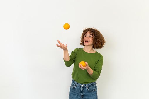 Studio portrait of a beautiful, young redhead woman holding a bunch of oranges