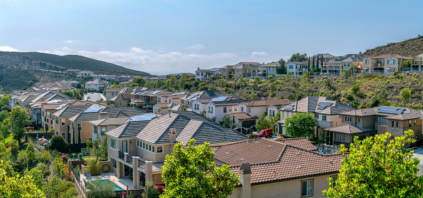 Upper middle class neighborhood near the Double Peak in San Marcos, California. High angle view of fenced large houses with yards near the mountains and a view of the sky at the back.