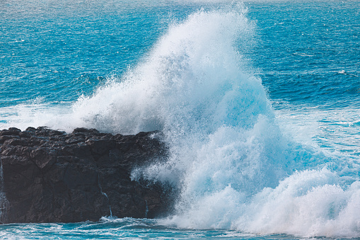 Black and white powerful ocean waves crashing against rocky coastline