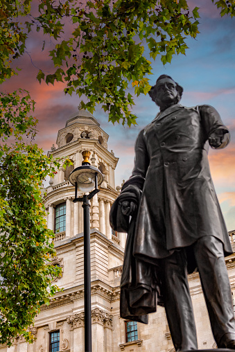 A statue of a gentleman standing in central London with buildings in its background
