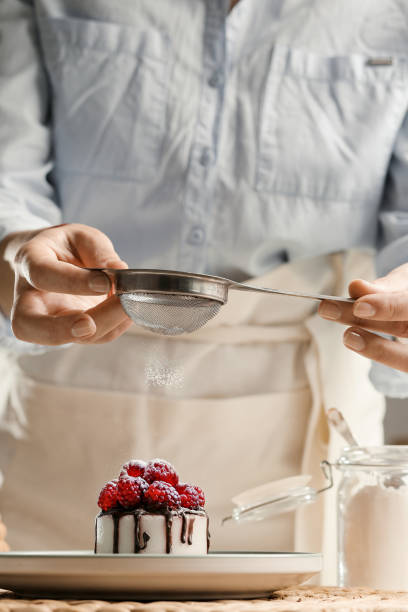 istock Housewife prepares a cupcake, sprinkles with sugar. 1447889384