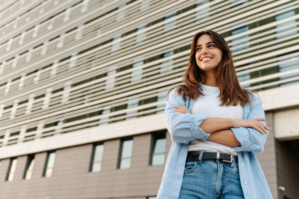 portret pewnej siebie młodej kobiety stojącej w mieście patrzącej w bok z radosnym wyrazem twarzy - campus university built structure outdoors zdjęcia i obrazy z banku zdjęć