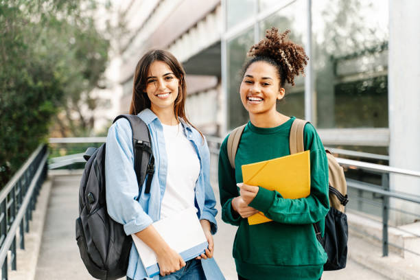 due amiche studentesse del college che sorridono pronte per le lezioni al campus universitario - studente foto e immagini stock