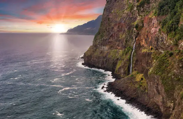 Photo of Madeira island - Dramatic sunrise over atlantic ocean with waterfall landscape from Miradouro do Veu da Noiva