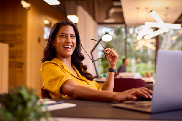 Donna d'affari matura con gli occhiali che lavorano sul computer portatile alla scrivania in ufficio - foto stock