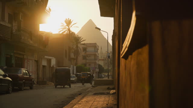 View of the pyramids of Giza from modern urban cityscape at sunset