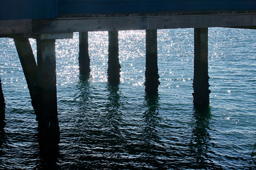 Sunlight reflections on the bay beneath the pier