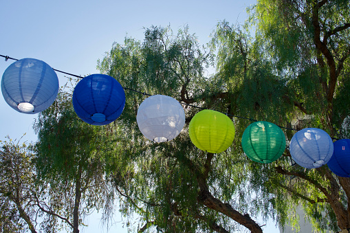 Colorful paper lanterns hanging from the string lights in the garden