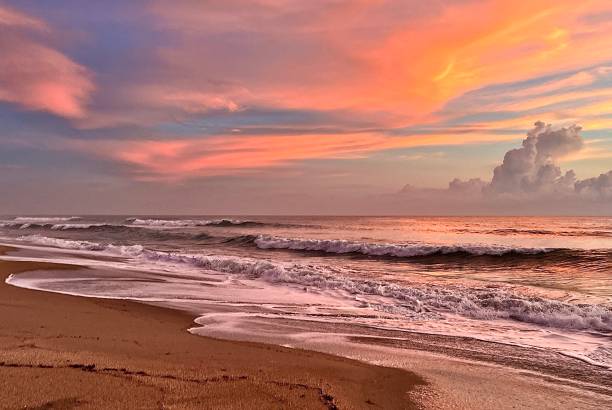 istock Orange and yellow clouds at dawn over a tropical seashore beach 1447893262