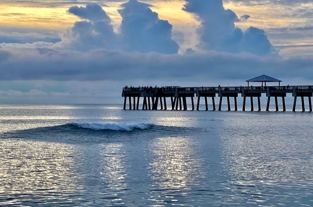 istock Wave breaking on a glassy reflecting ocean at dusk with a pier in the background 1447893404