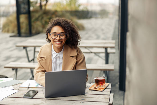 istock Afro american woman freelancer working remotely and drinking tea while sitting on cafe terrace 1447893500