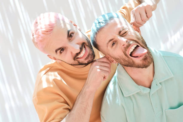 屋外で日光の効果を持つ白い背景に変な顔をしている2人の男性の接写 - real people blue white friendship ストックフォトと画像