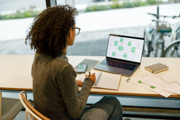istock Afro american woman freelancer working laptop and making notes while sitting in cozy coworking 1447896159