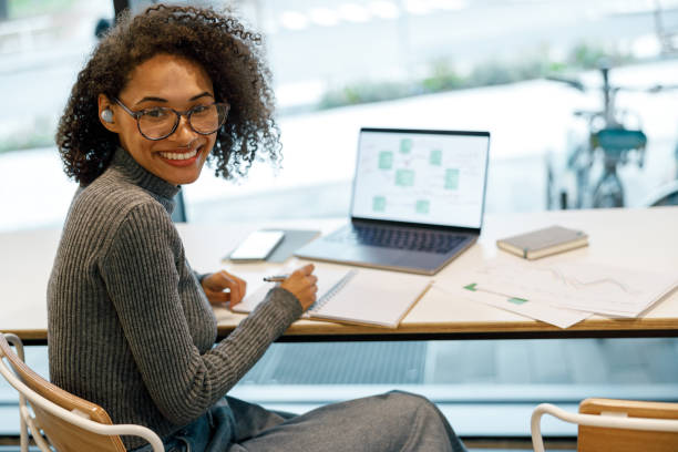 istock Smiling woman freelancer working laptop and making notes while sitting near windows in cozy cafe 1447896222