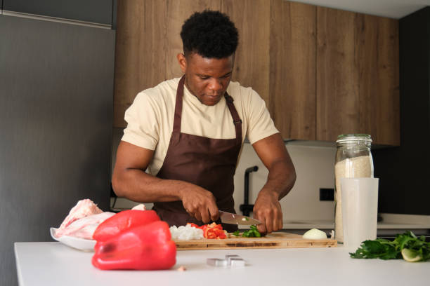 istock Young black man cutting celery to prepare chicken recipe. 1447898126
