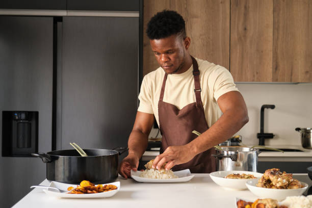 istock Young black man serving fried chicken mince on rice on a plate. 1447898144